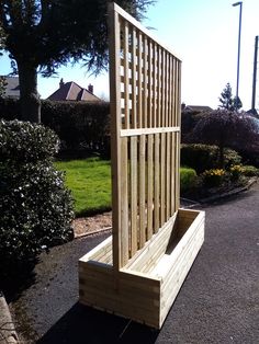 a wooden bench sitting in the middle of a road next to bushes and trees on both sides