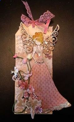 an altered paper doll with flowers and laces on it's back, sitting in front of a black background