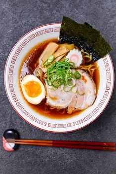 a bowl of ramen with an egg and chopsticks next to it on a table