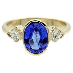 a yellow gold ring with a blue sapphire and three diamonds