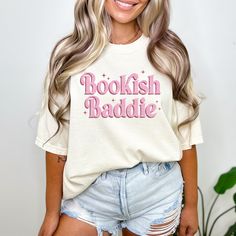 a woman wearing a bookish raddie t - shirt and denim shorts with her hands in her pockets