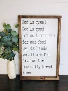 a wooden frame with the words god is great on it next to a potted plant