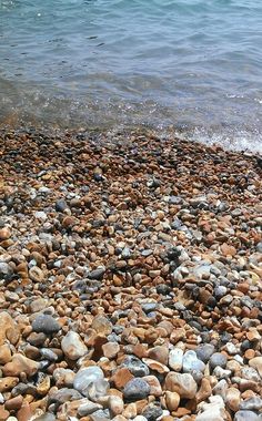 rocks and pebbles on the beach with water in the backgroung behind them