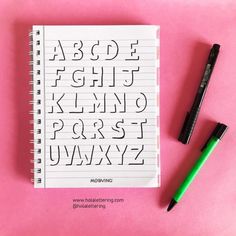 a notebook with the letters and numbers drawn on it next to a green marker,