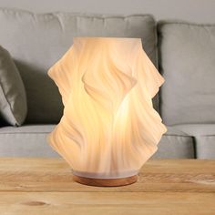 a white vase sitting on top of a wooden table next to a gray couch in a living room