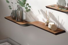 two wooden shelves with candles, vases and plants on them next to each other