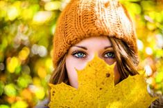 a woman holding up a yellow leaf in front of her face