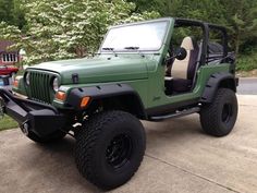 a green jeep is parked in front of some trees