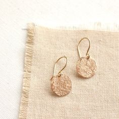 Sweet little discs of shimmering gold.  I have given the metal a "raw silk" texture.  It is subtle and unique.  Discs measure 1/2".  Total length 1".  Handmade shepherd hook earwires.  14k gold fill.  About 14k gold fill: 14K gold filled wire is a professional jewelers grade wire. Gold filled wire is not plated. It is a tube of solid 14K gold mechanically bonded to a brass or silver base. There is 100 times more gold in gold filled than in gold plate wire. This layer of gold must be a minimum of Gold Hammered Circle Earrings, Gold Brass Round Disc Earrings, Delicate Gold Metal Earrings, Gold Round Disc Earrings For Pierced Ears, Gold Circular Earrings As Gift, Gold Round Disc Earrings, Gold Circular Earrings For Gift, Hammered Rose Gold Brass Earrings, Gold Circle Earrings As Gift