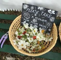 two baskets with flowers in them sitting on a bench next to a sign that says please take a flower for your hair