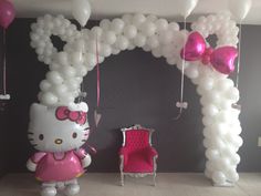 a hello kitty balloon arch and chair in a room with balloons on the wall,