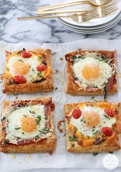 four square pieces of bread topped with eggs and tomatoes on top of each other next to a fork