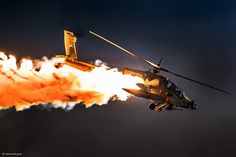 a helicopter flying through the air with fire coming out of it's back end