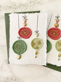 two christmas cards with ornaments on them, one is green and the other is red