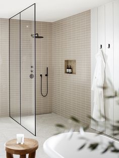 a bathroom with a walk in shower next to a white bath tub and wooden stool