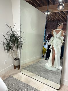 a woman is standing in front of a mirror wearing a white dress and high heels