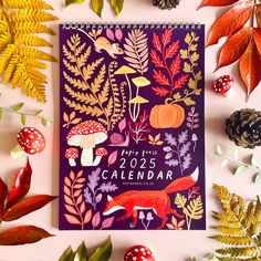 a purple calendar surrounded by autumn leaves and mushrooms