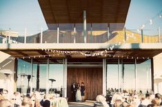 a bride and groom standing in front of a large group of people