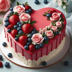 a heart shaped cake decorated with fresh berries and blueberries