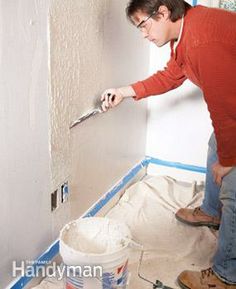 a man is painting the wall with white paint and a pair of scissors in his hand