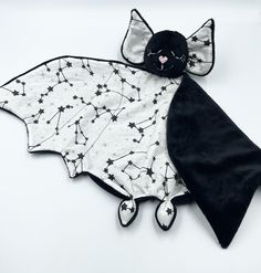 a black and white bat stuffed animal with stars on it's back, laying down