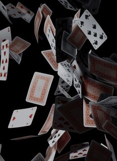 many playing cards are falling down into the air on a black background with red and white designs