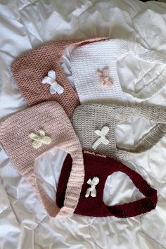 three knitted baby hats laying on top of a white bed next to each other