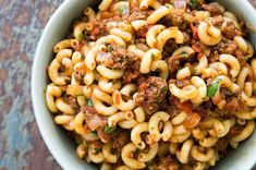 a bowl full of pasta with meat and sauce in it on top of a table