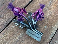 purple flowers are sitting on top of a metal comb that says, an embellishment