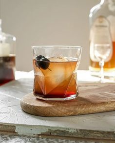 a glass filled with liquid sitting on top of a wooden cutting board