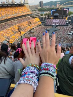 two hands with matching bracelets at a sporting event in front of an empty stadium