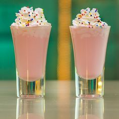 two glasses filled with ice cream and sprinkles on top of a table