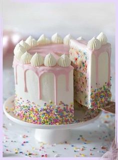 a white cake with pink frosting and sprinkles on it's side