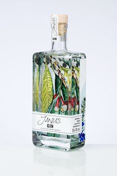 a bottle of gin with leaves and flowers painted on the front, sitting on a white surface