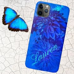 a blue butterfly sitting next to a phone case with the name lauren on it and a flower