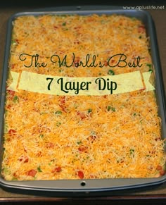 the world's best 7 layer dip in a baking pan with cheese on top