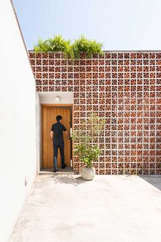 a man standing in front of a wooden door with plants growing on the top of it