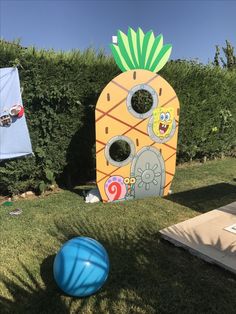 an inflatable ball sits on the grass next to a fake pineapple house