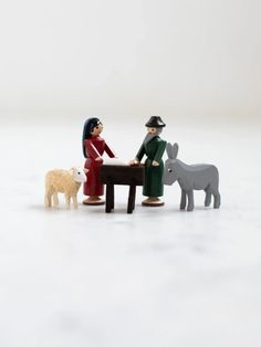 two figurines sitting at a table with sheep