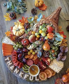 a platter filled with fruits and vegetables on top of a wooden table next to leaves