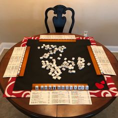 a table topped with lots of dice and paper on top of it next to a chair