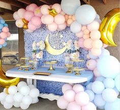 a table topped with balloons and desserts next to a wall covered in stars and moon