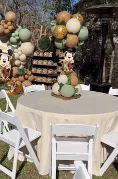 there is a table set up with mickey mouse decorations on it and balloons in the air