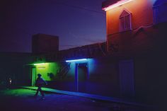 a person walking in front of a building with graffiti on the side and neon lights