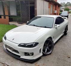 a white sports car parked in front of a house