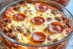 a pizza casserole with pepperoni and cheese in a glass dish on a table