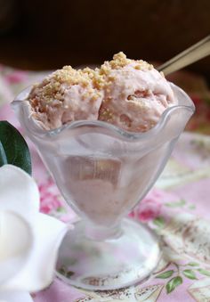 two scoops of ice cream sit in a glass bowl on a floral tablecloth