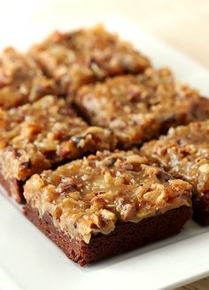 there are several brownies on the plate with nuts all over them and one is cut into squares