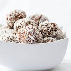 a white bowl filled with chocolate truffles covered in powdered sugar and sprinkles