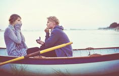 two people are sitting in a boat on the water and one is holding a yellow pole